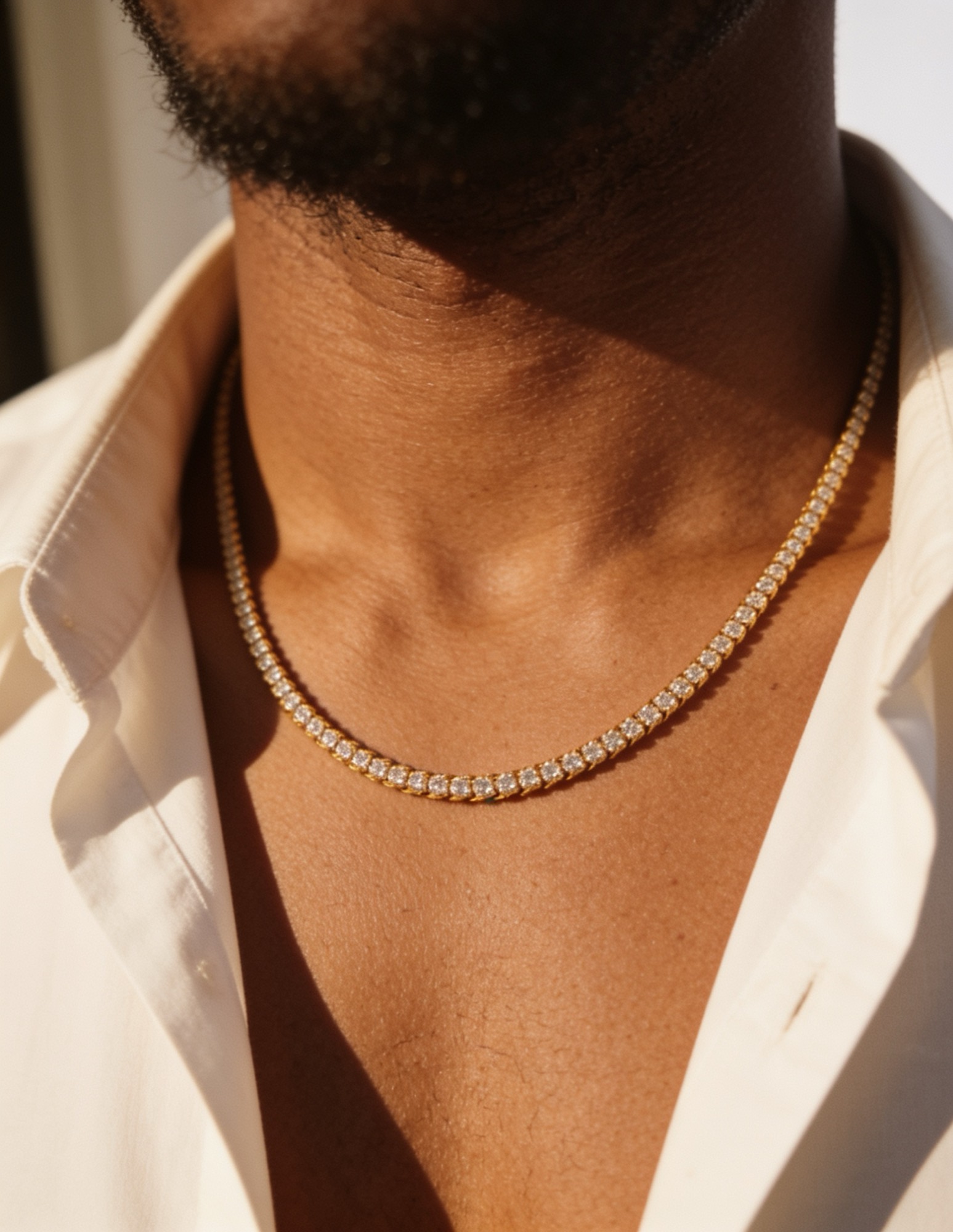 A man wearing a gold diamond line chain over an open-collar shirt