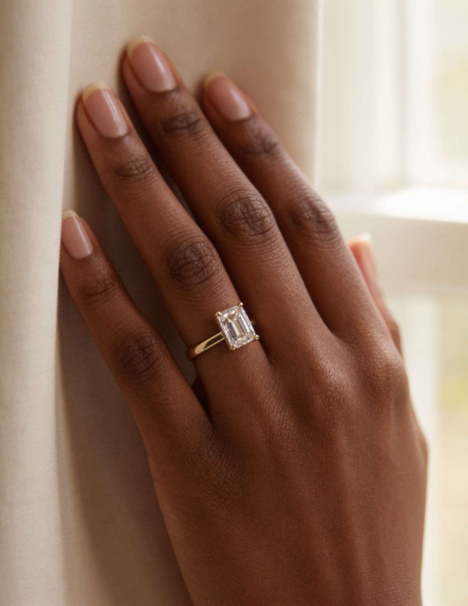 Emerald-cut diamond solitaire in yellow gold, worn on the hand