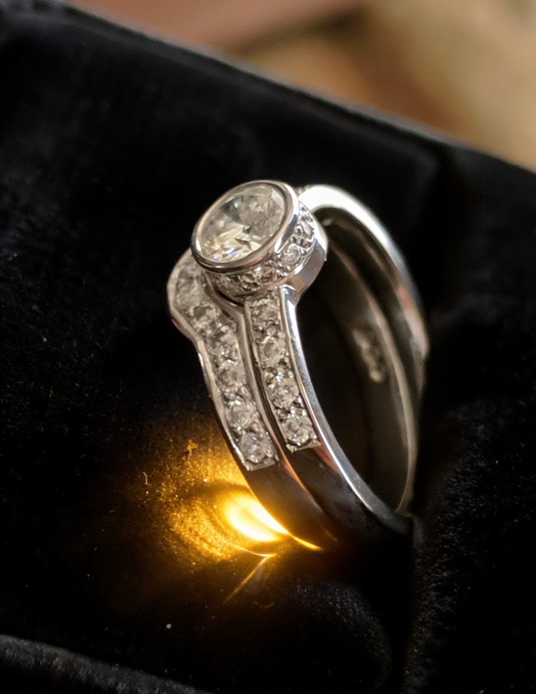 White-gold bezel-set diamond solitaire with a matching pave band