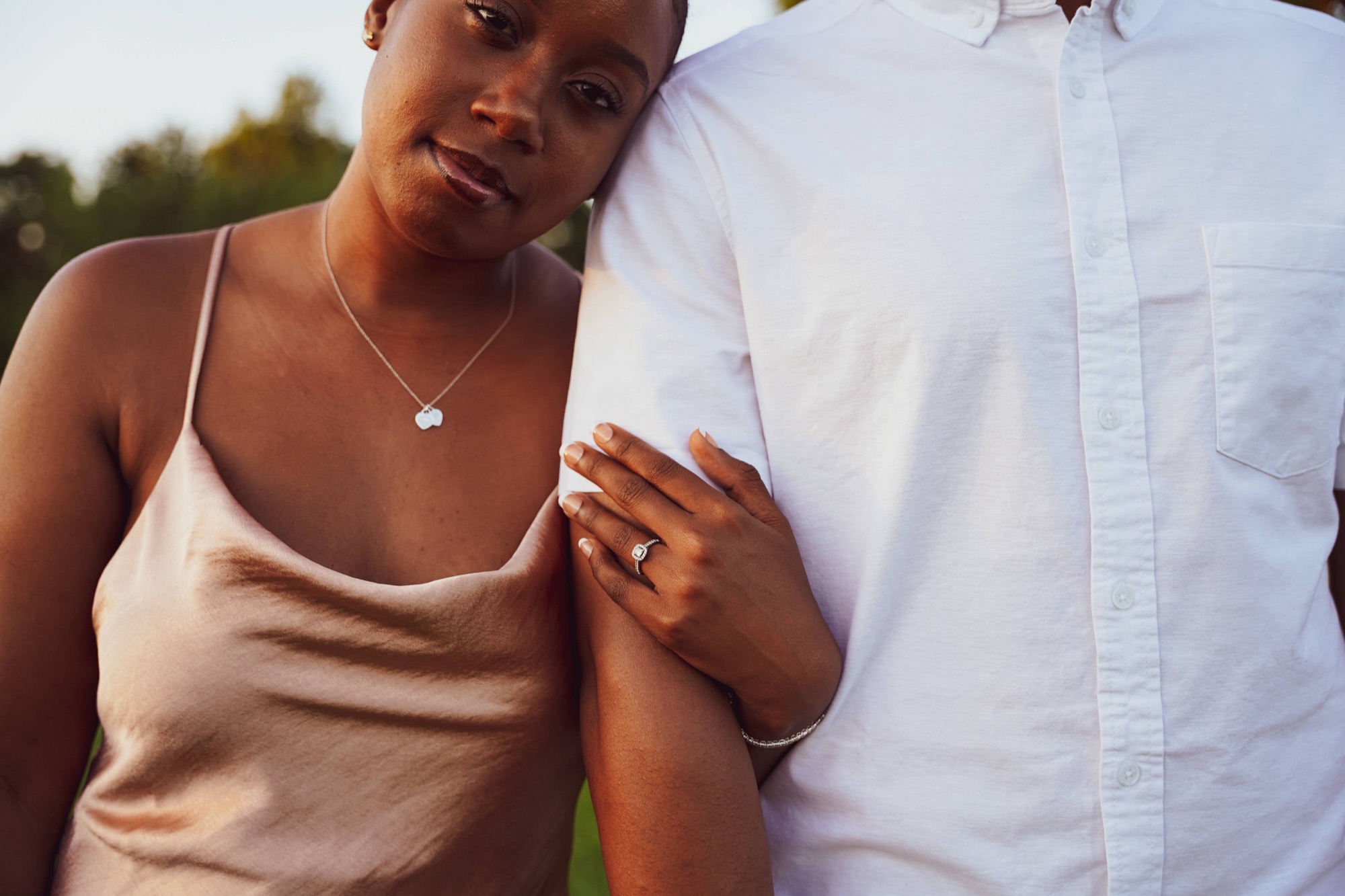 A couple's hands resting together by candlelight, wearing gold rings